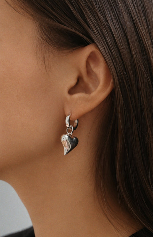 Close-up of a person wearing a silver heart-shaped earring.