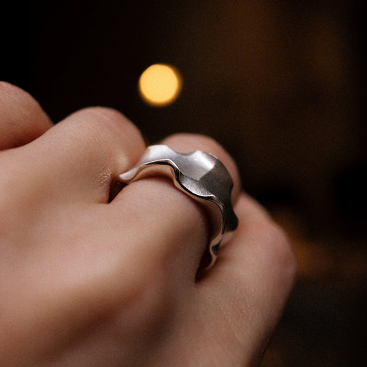 Close-up of a hand wearing a silver ring with a blurred background