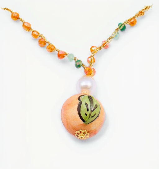 Necklace with a peach-colored bead featuring a green leaf design on a white background