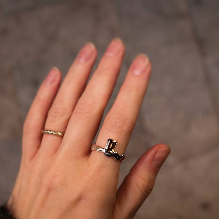 Hand wearing two rings on a blurred background