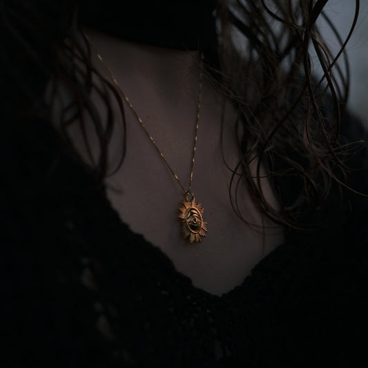 Necklace with a lion pendant worn by a person in a dark setting