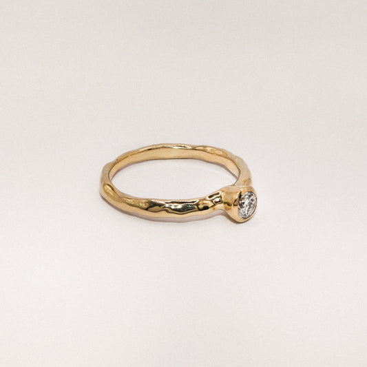 Gold ring with a diamond on a light gray background