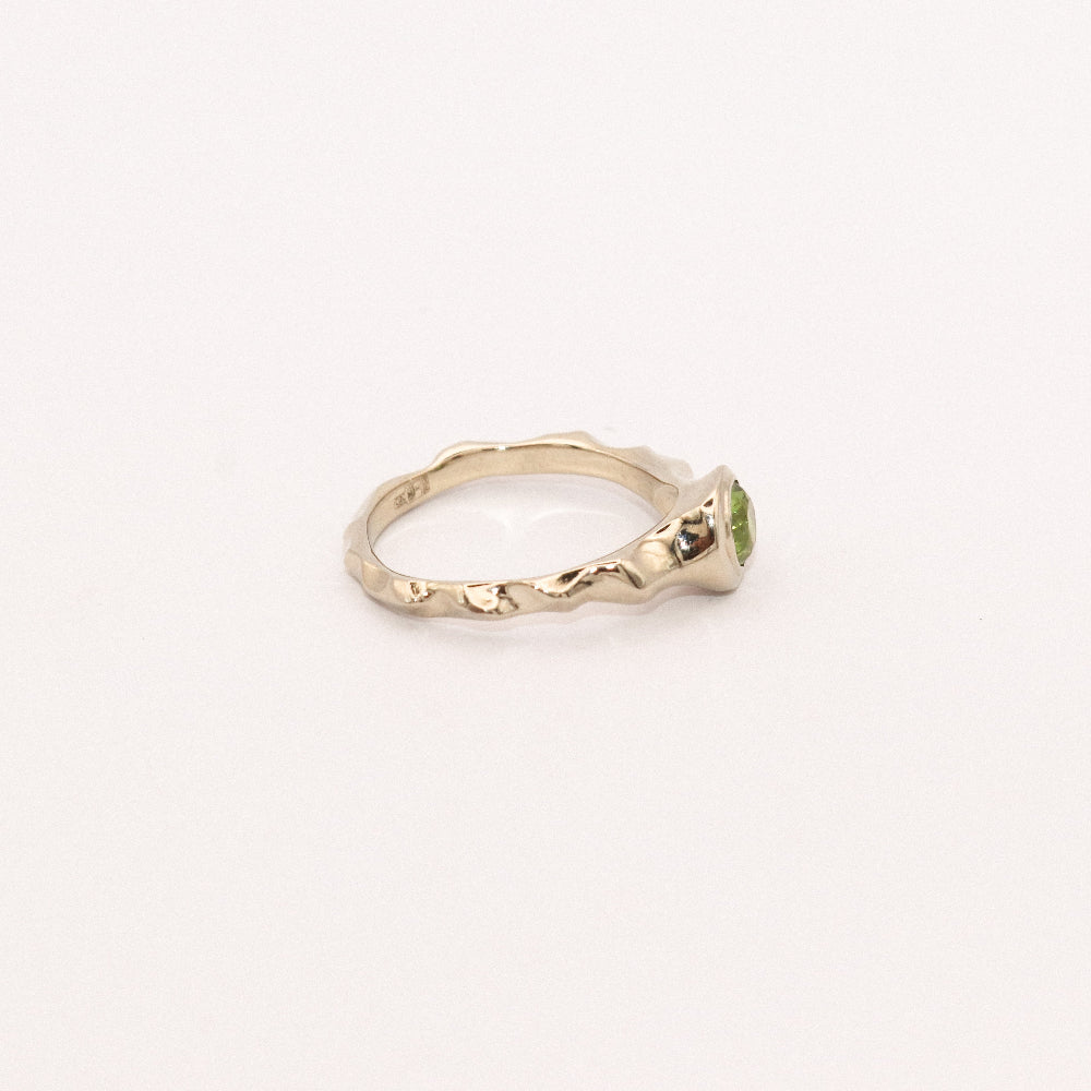 Gold ring with a green gemstone on a white background