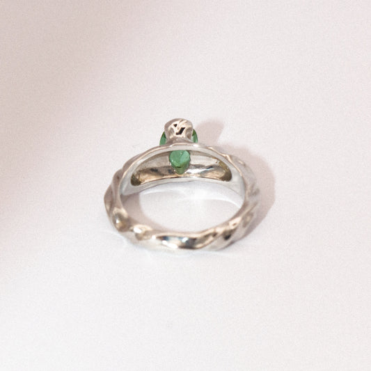 Silver ring with green gemstones on a white background