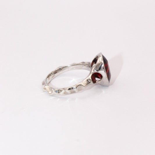 Silver ring with a red gemstone on a white background
