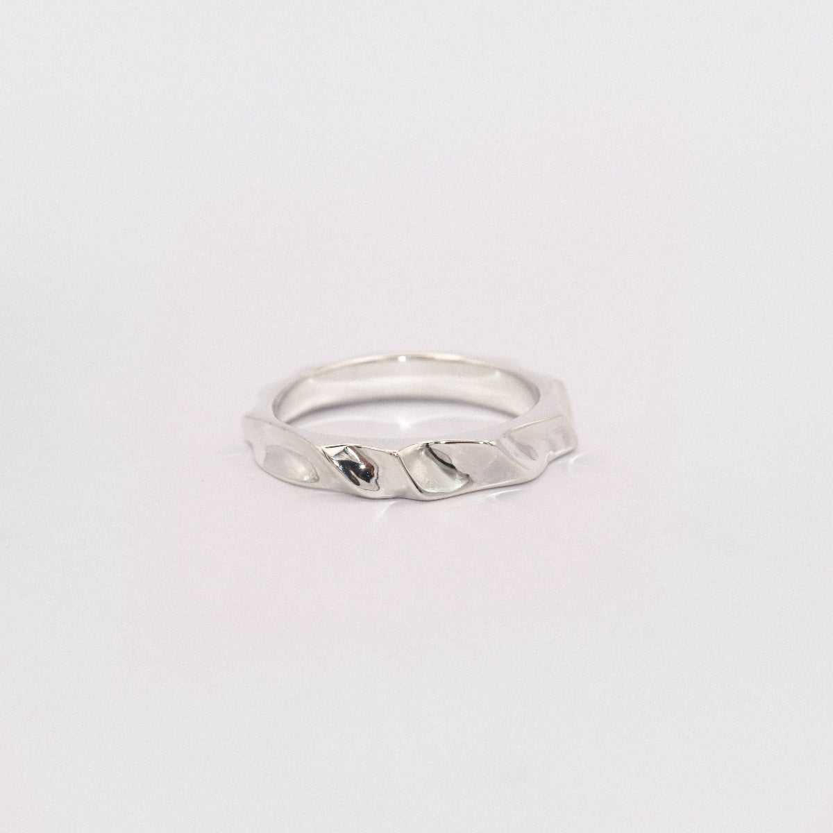 Silver ring with a textured design on a light gray background
