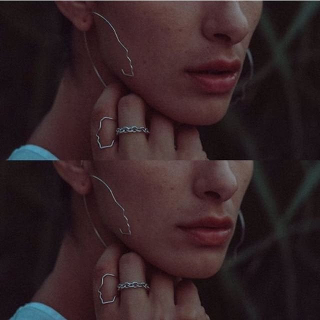 Close-up of a person wearing silver earrings and rings with a blurred background