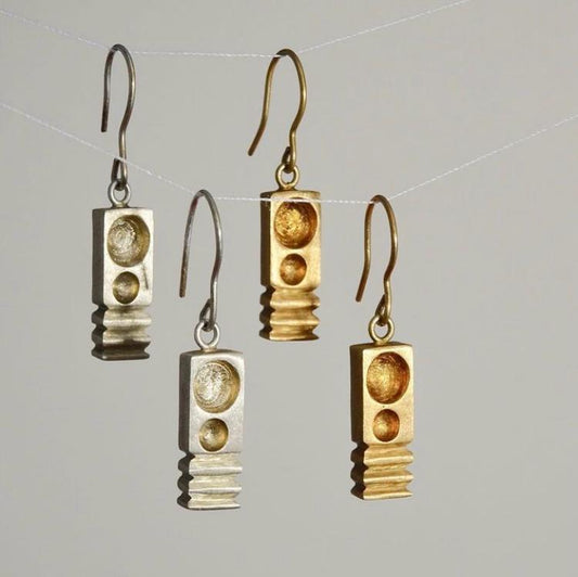 Pair of gold and silver earrings on a gray background
