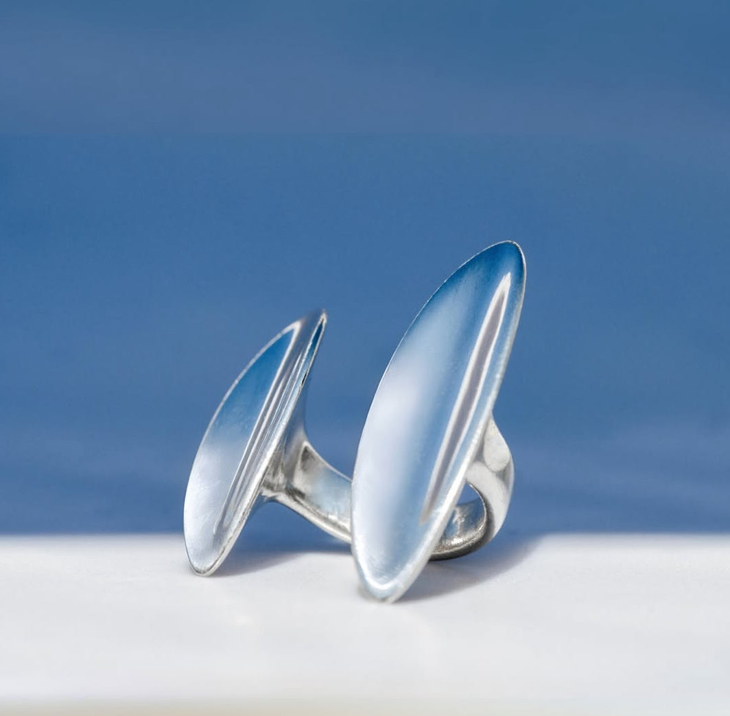 Silver earrings on a white surface with a blue background