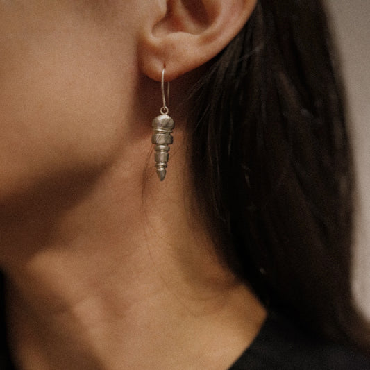 Close-up of a person wearing a silver spiral earring with a blurred background