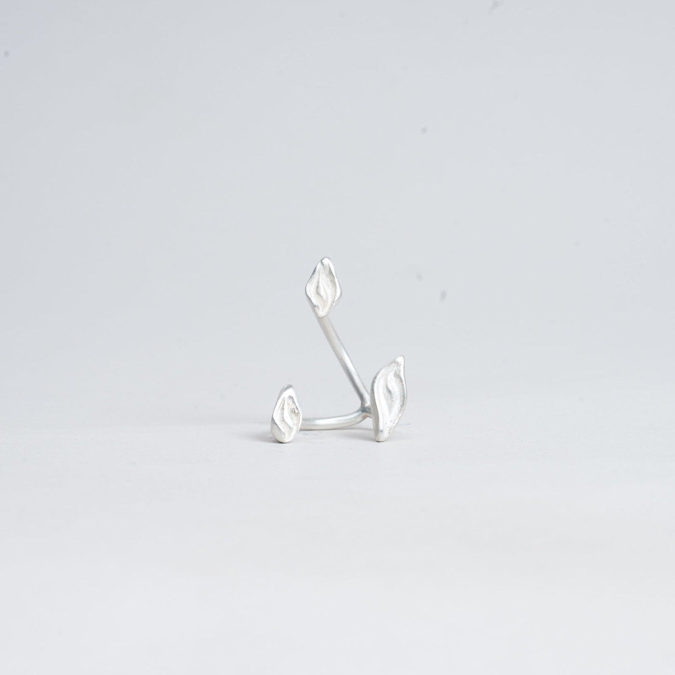 Silver earring on a light gray background