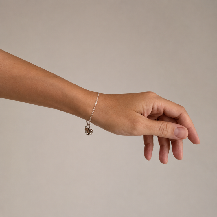 Hand wearing a silver bracelet on a plain white background