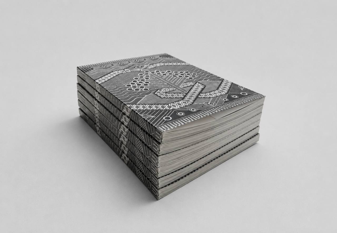 A stack of patterned notebooks or books with black and white geometric designs, photographed on a clean light gray background.