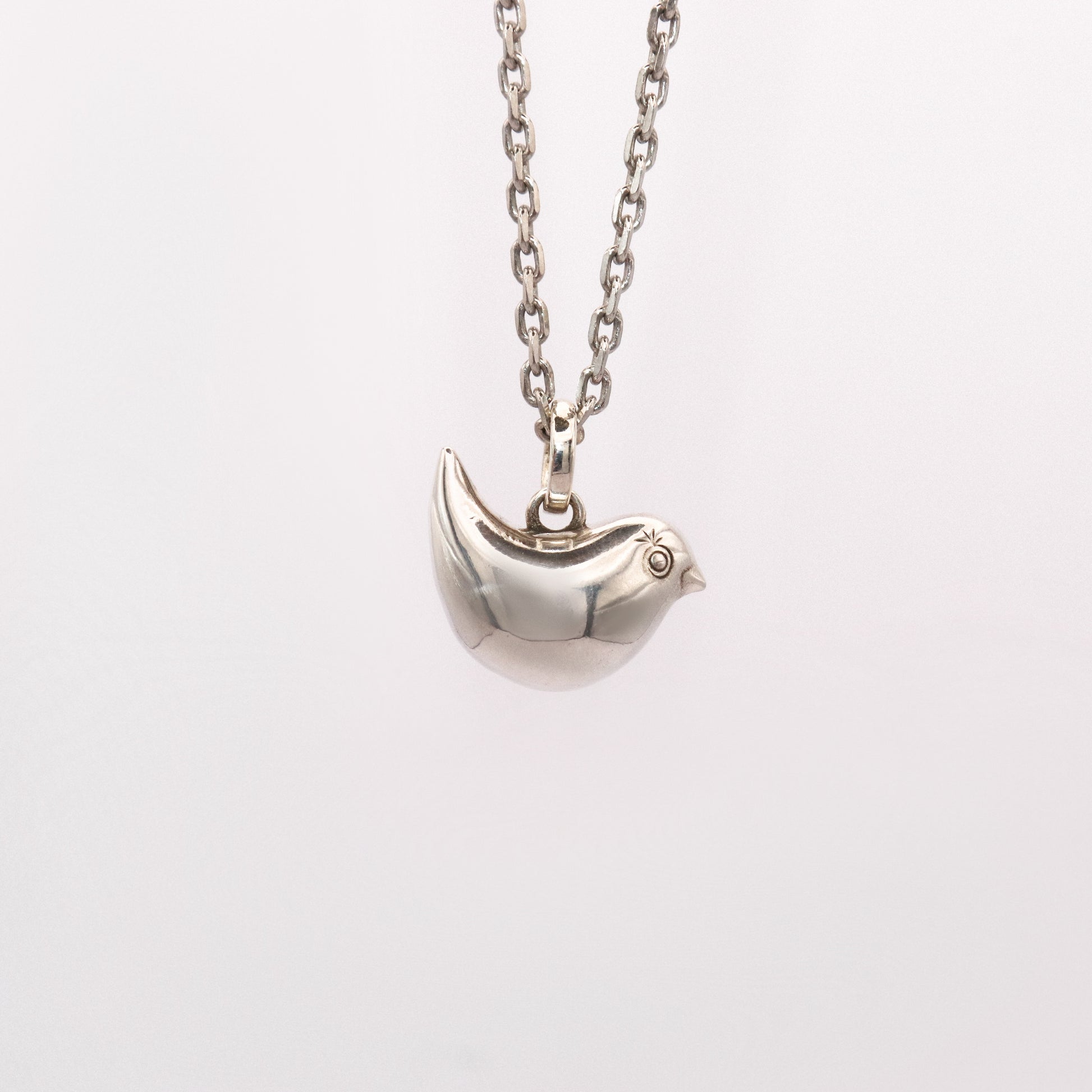 Silver bird-shaped pendant on a chain against a white background