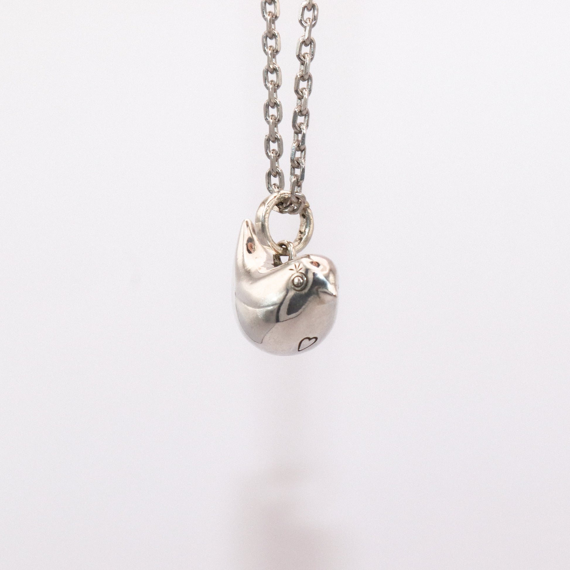 Silver necklace with a heart-shaped pendant on a white background