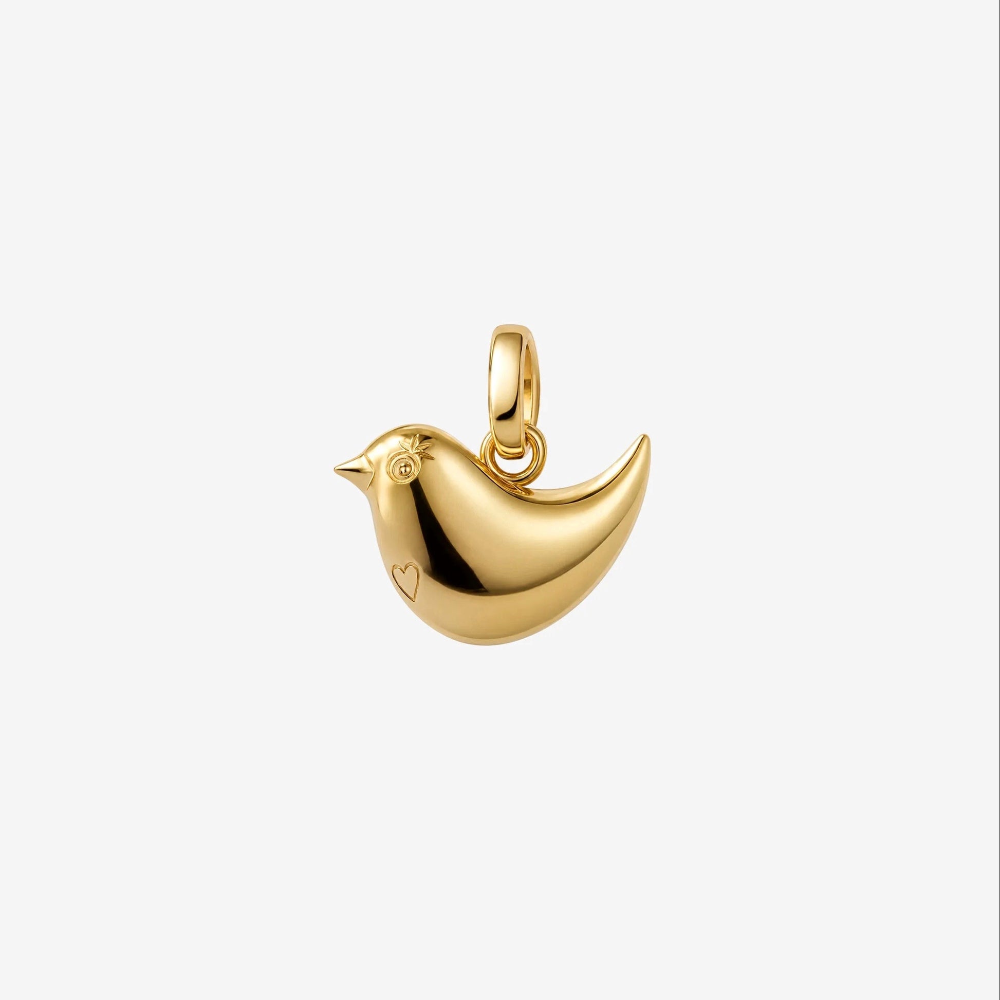 A polished gold bird charm pendant with a small heart detail on its side, shown against a plain light gray background.