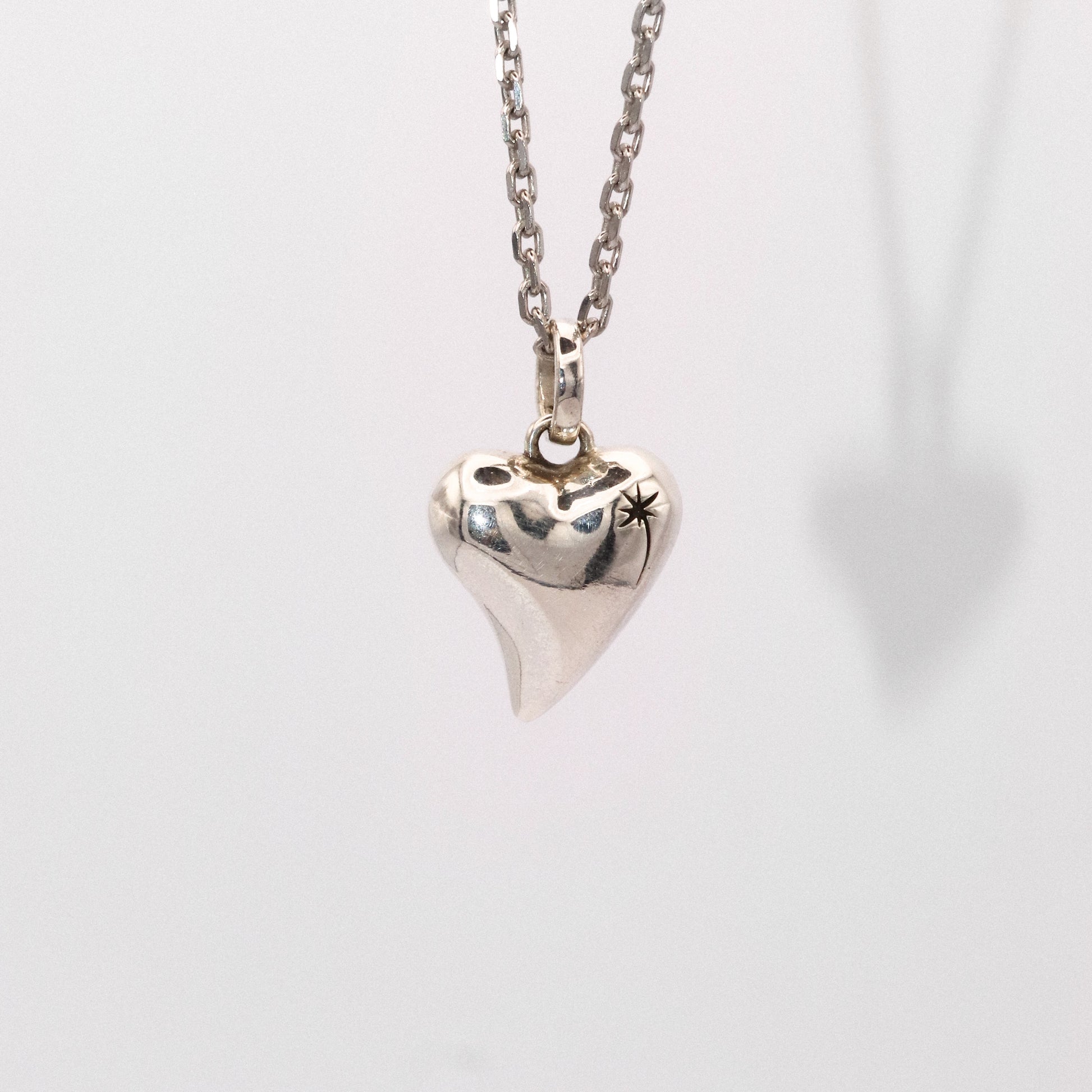 Silver heart-shaped pendant necklace on a light gray background