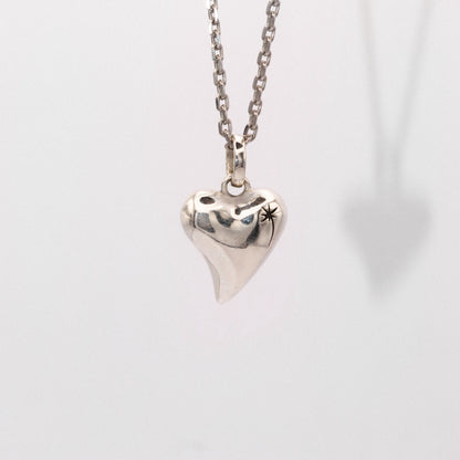 Silver heart-shaped pendant on a chain against a light gray background