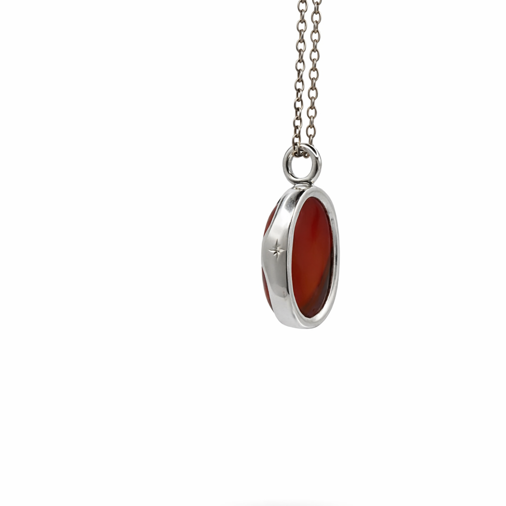Silver pendant with a red stone on a white background