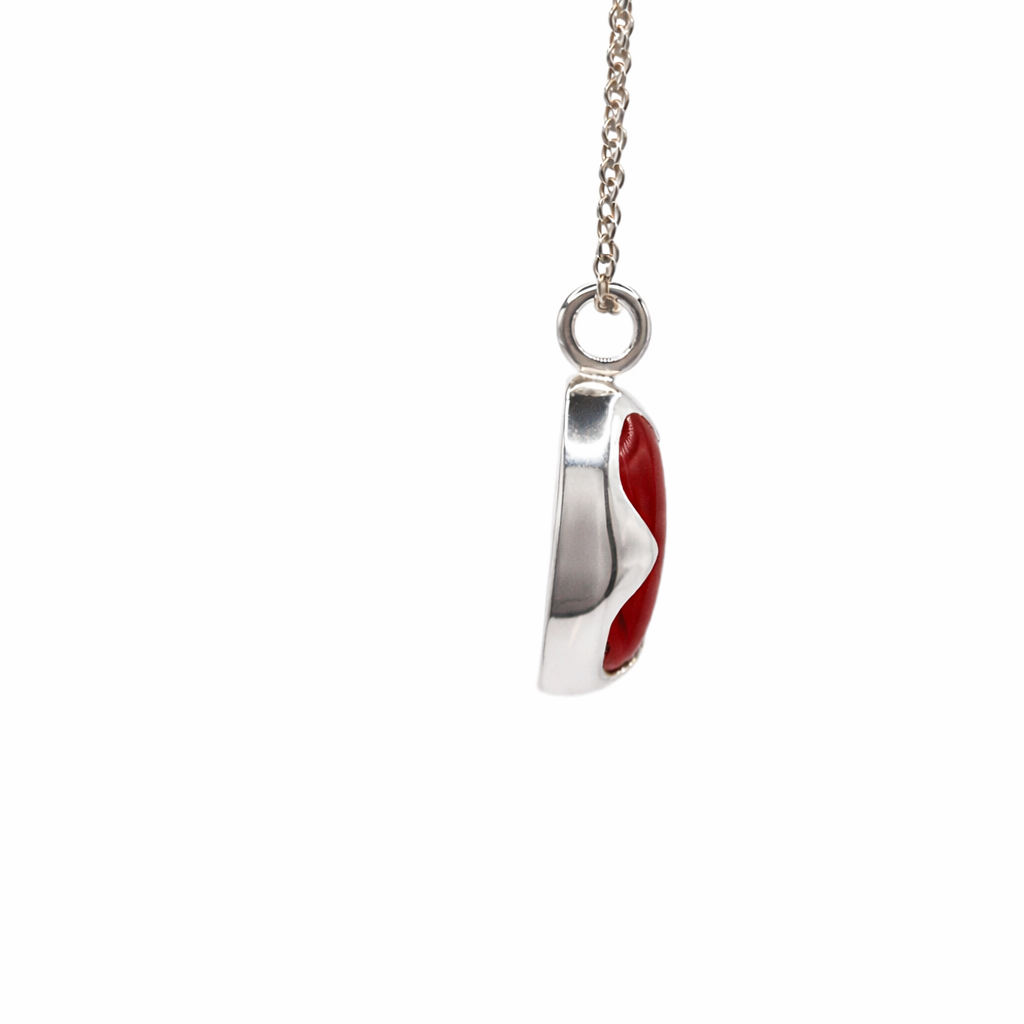 Silver necklace with a red pendant on a white background