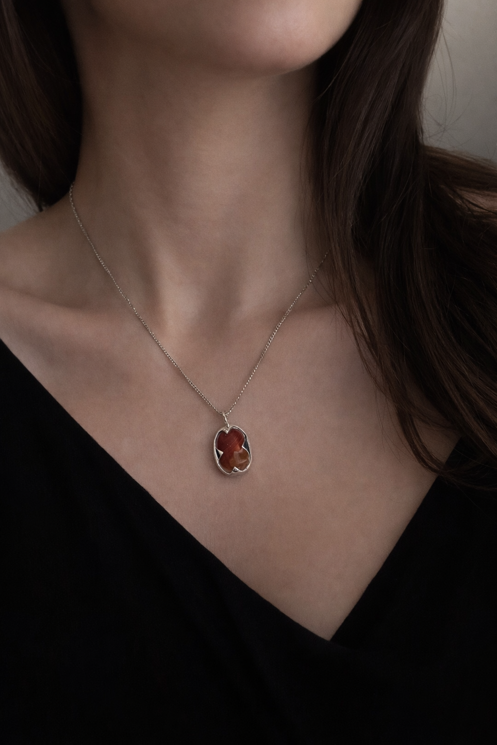 Necklace with a pendant worn by a person against a neutral background