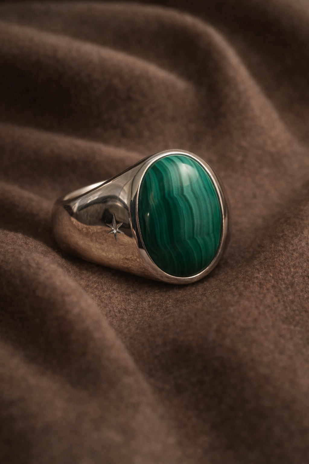 Silver ring with a green stone on a brown fabric background