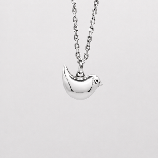 Silver necklace with a bird pendant on a light gray background