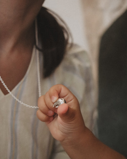 Close-up of a hand holding a silver ring with a blurred background