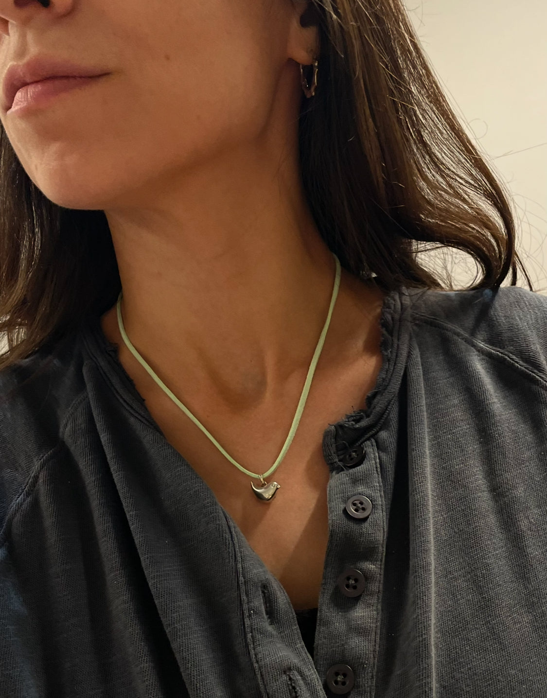 Close-up of a person wearing a necklace with a small pendant.