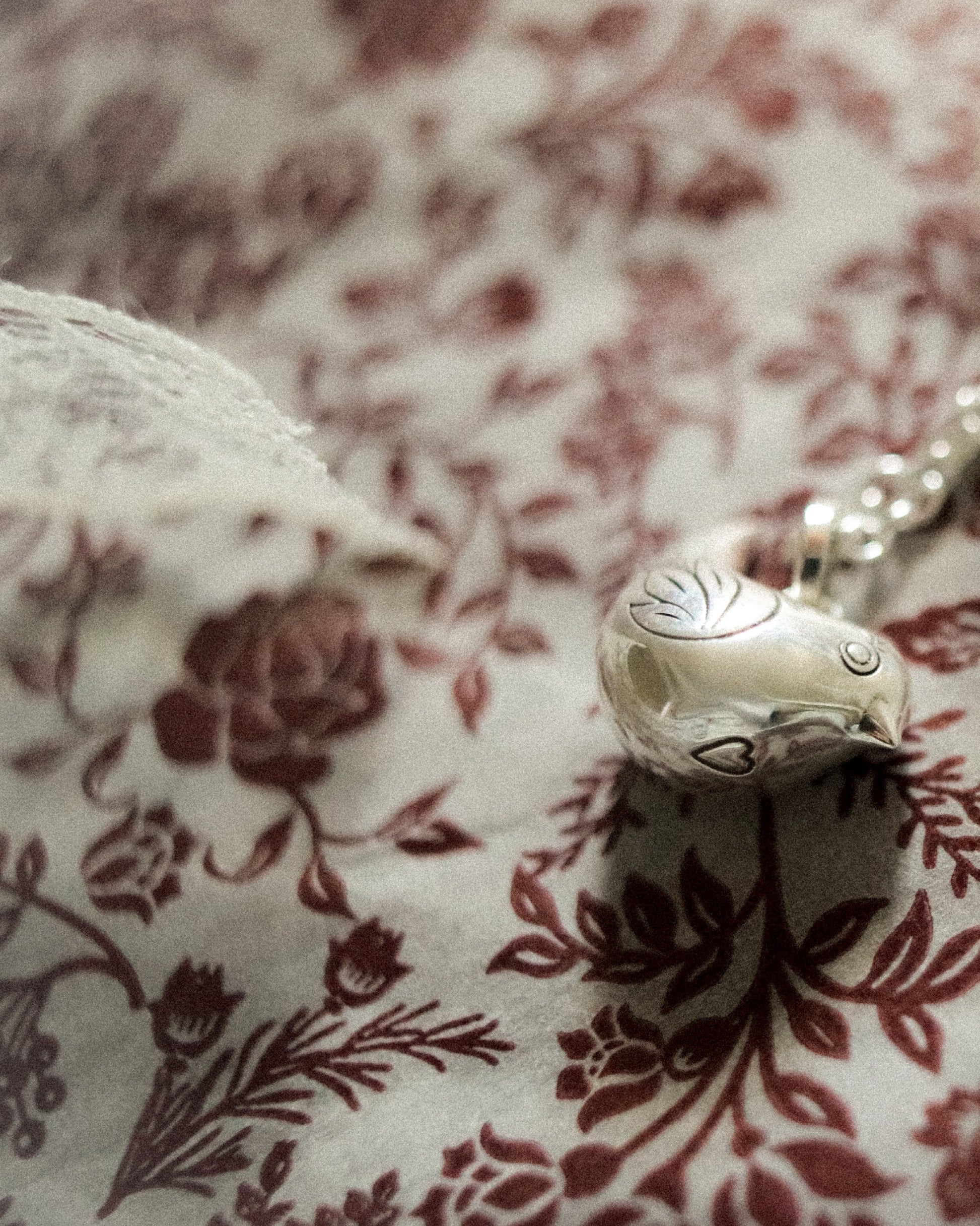 Silver charm on a floral fabric background