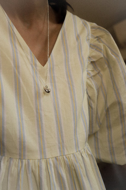 Close-up of a person wearing a yellow and blue striped dress with a necklace.