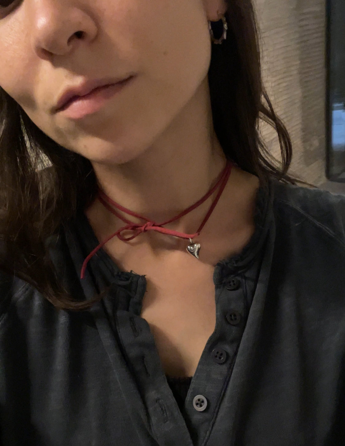 Close-up of a person wearing a red choker necklace with a small heart pendant.