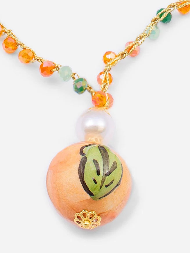 Necklace with a peach-colored bead featuring a green leaf design on a white background