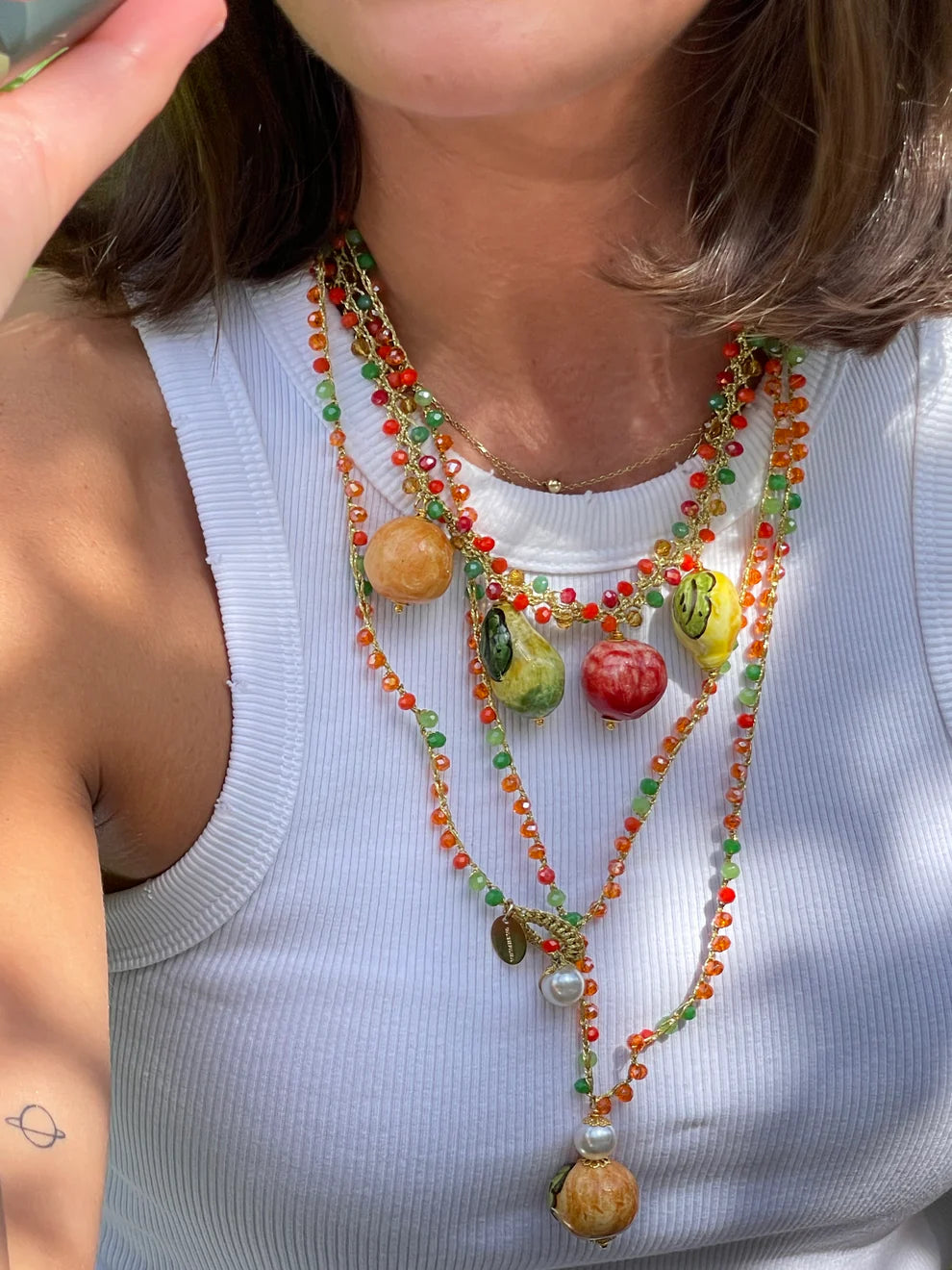 Person wearing a colorful beaded necklace with fruit-shaped beads.