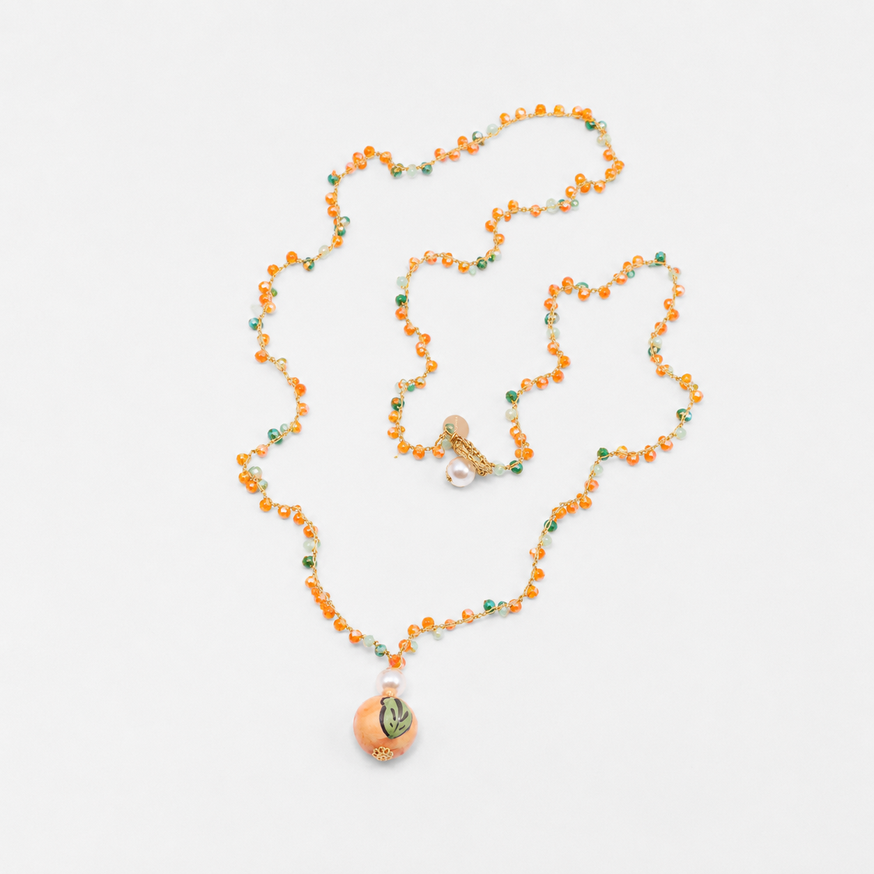 Necklace with orange beads and a decorative pendant on a white background