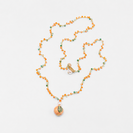 Necklace with orange beads and a decorative pendant on a white background