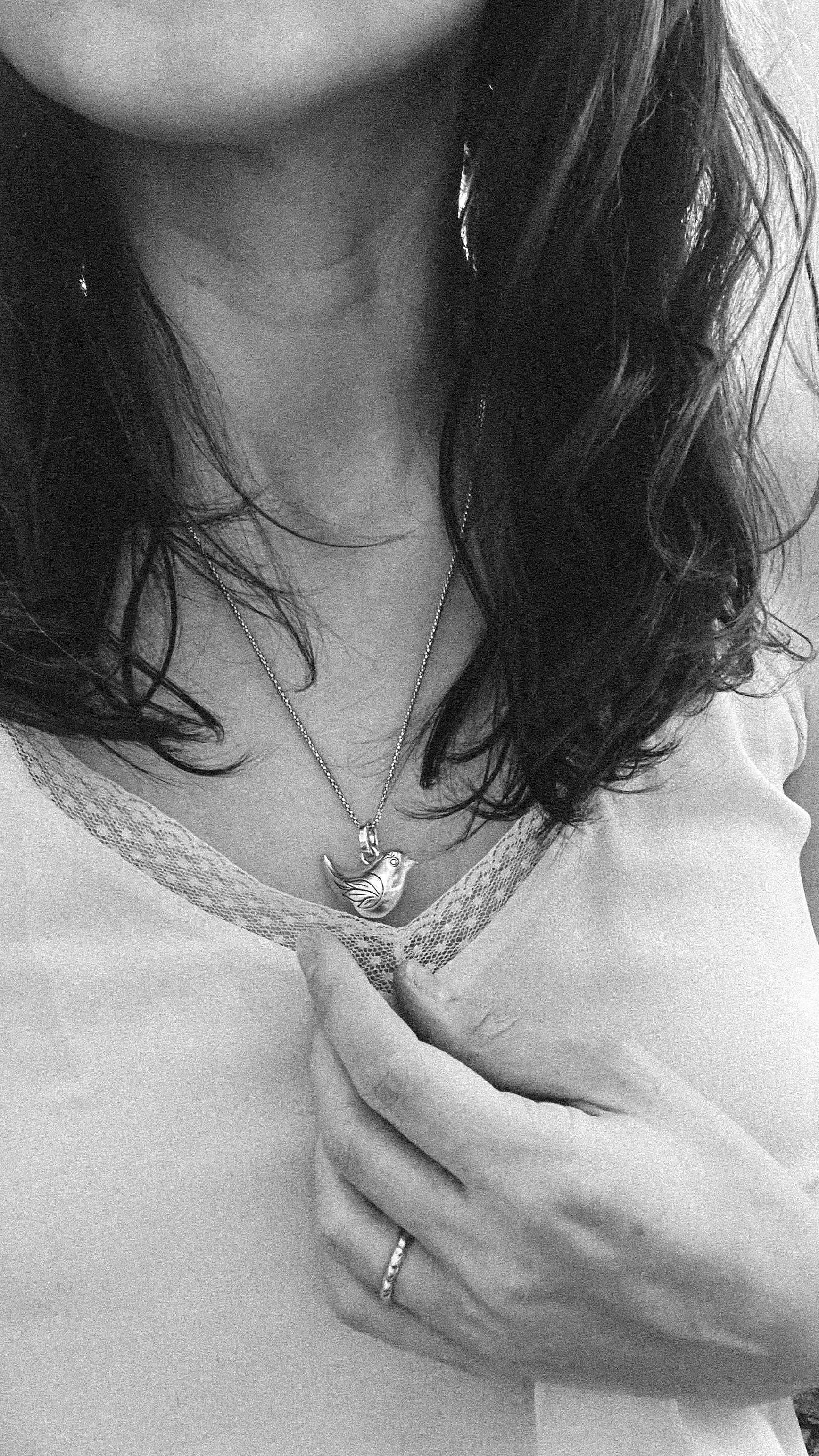 Close-up of a person wearing a necklace with a heart pendant.