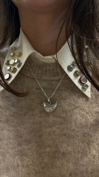 Necklace with a pendant worn by a person, close-up on a neutral background