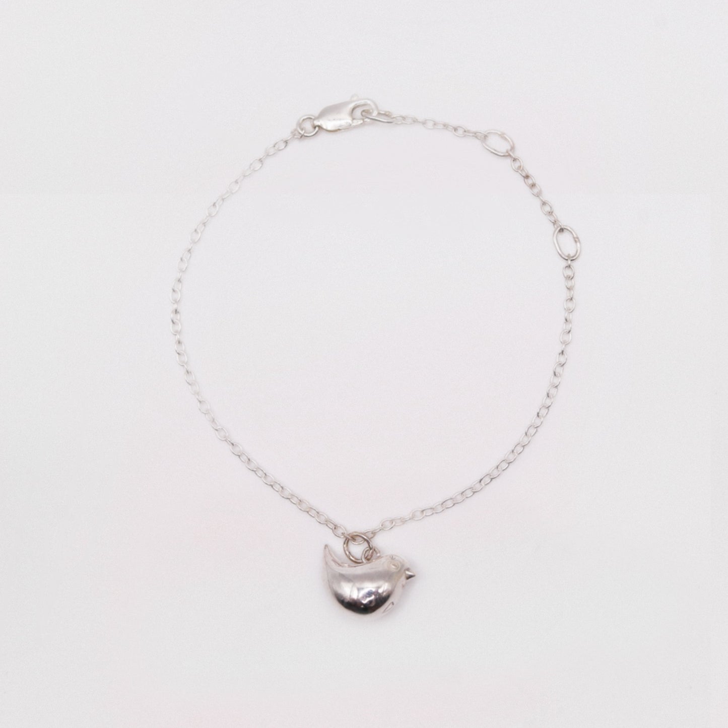Silver bracelet with a heart-shaped charm on a white background