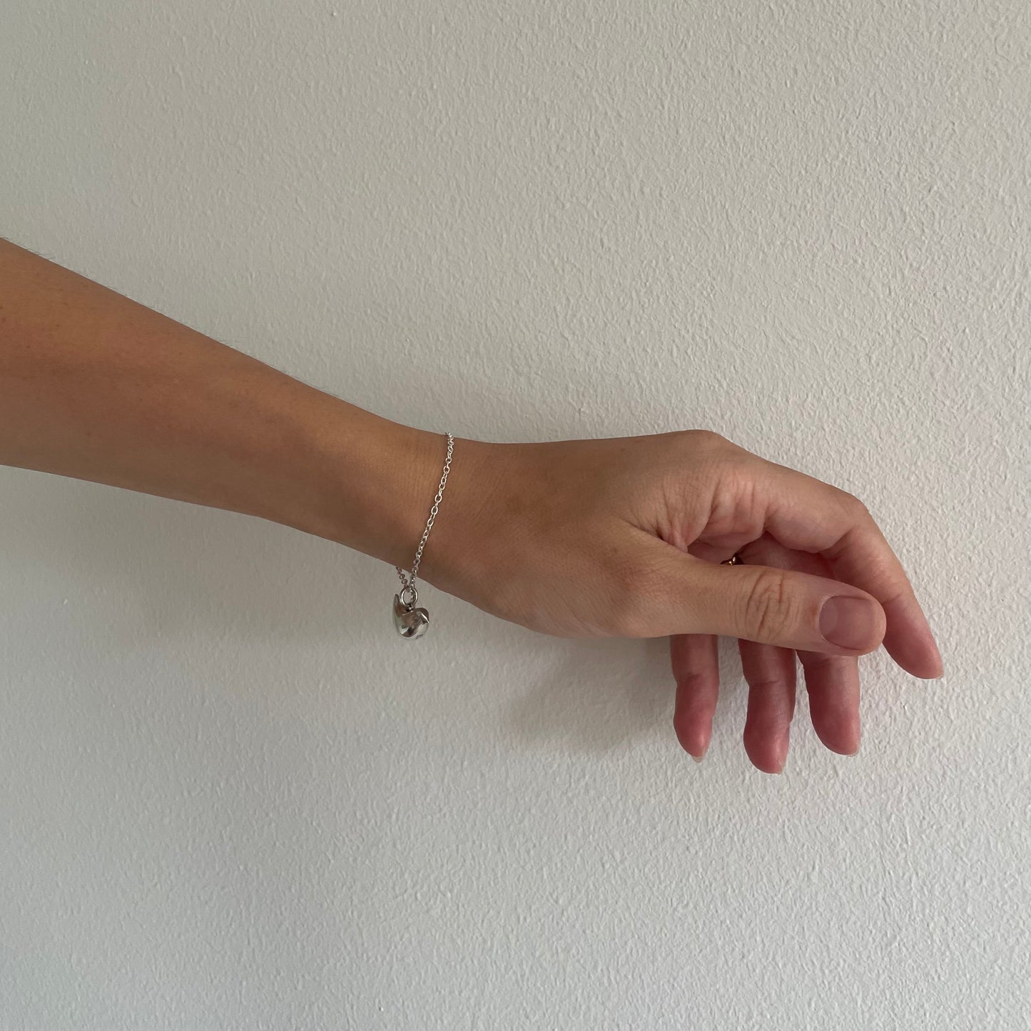 Hand wearing a silver bracelet on a plain white background