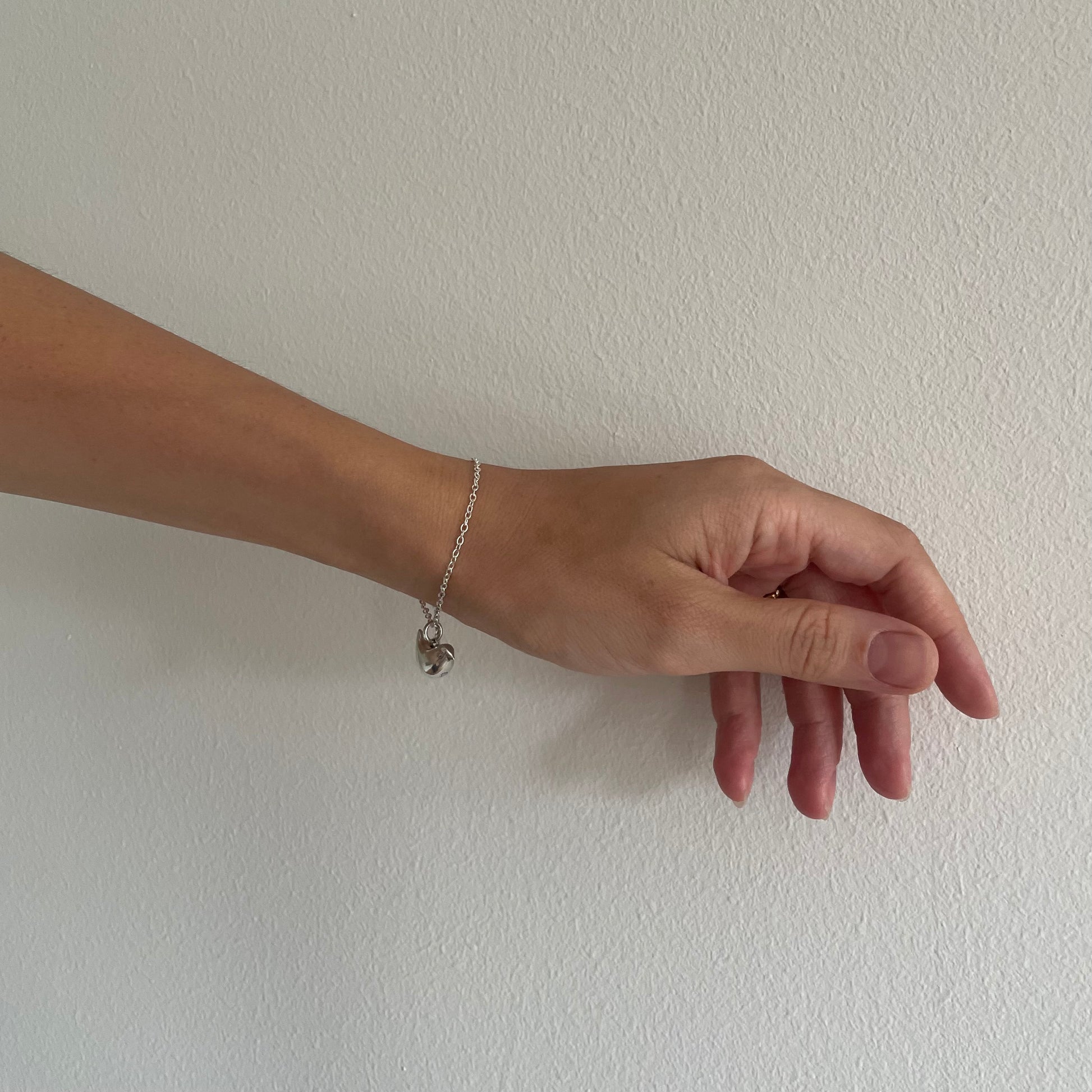 Hand wearing a silver bracelet on a plain white background