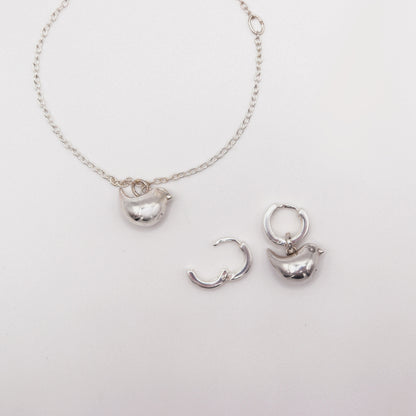 Silver necklace with pendant and hoop earrings on a light gray background