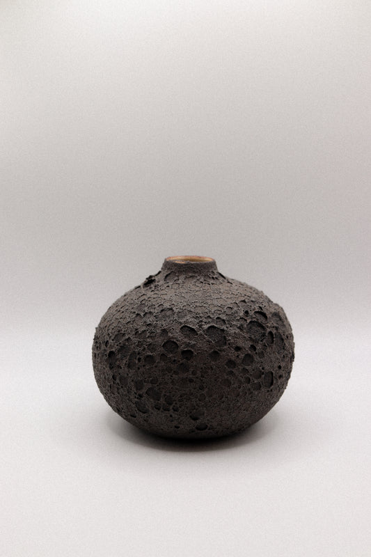 Black textured ceramic vase on a white background