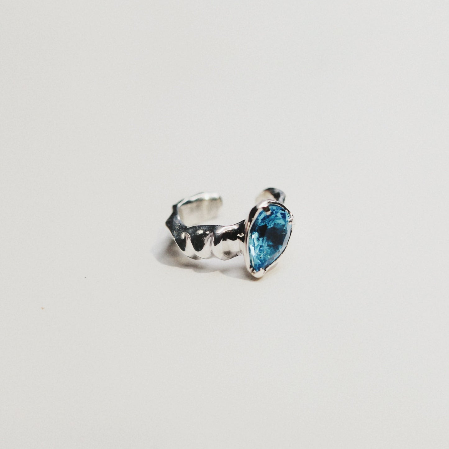 A silver ring featuring a marquise-cut light blue gemstone, photographed against a seamless white background.