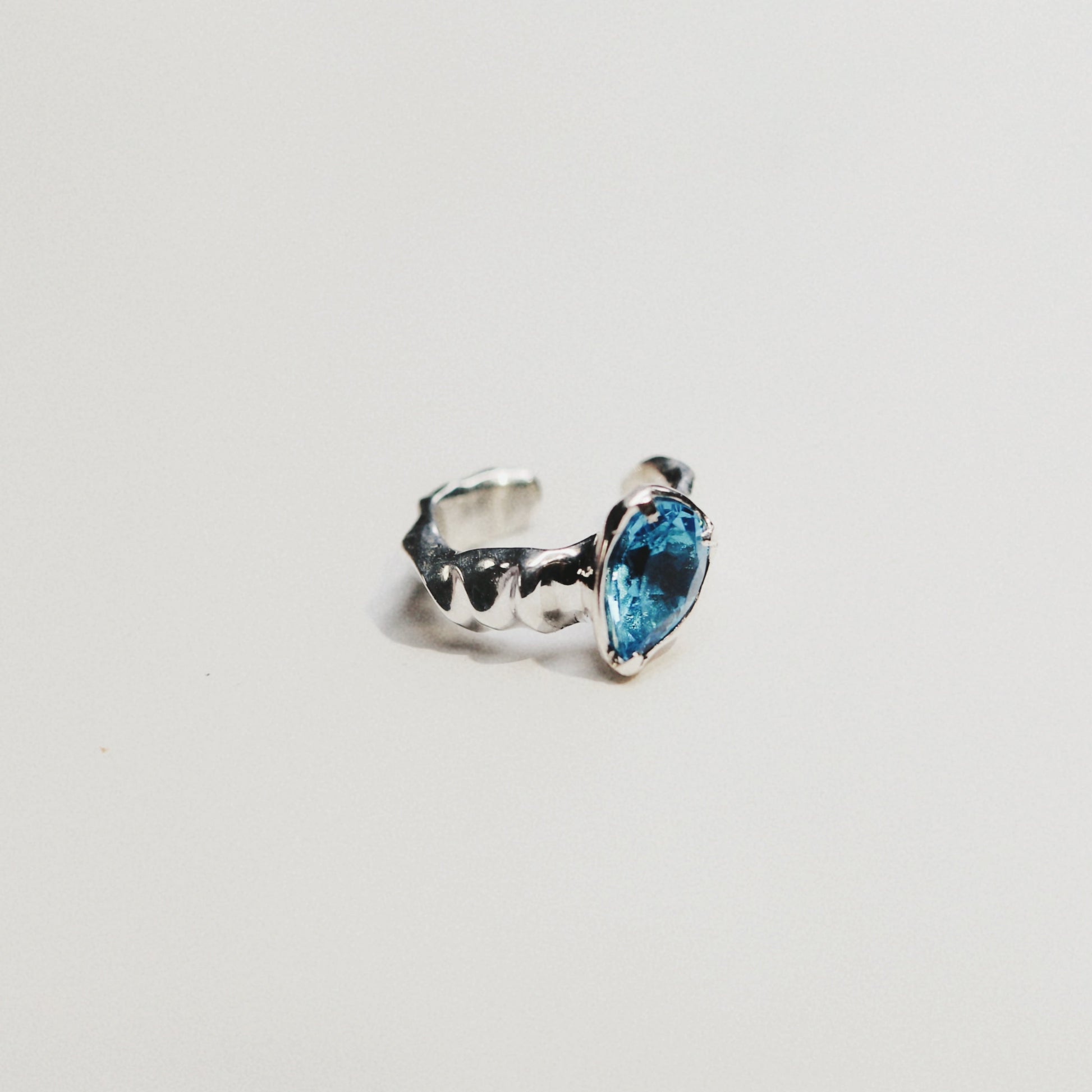 A silver ring featuring a marquise-cut light blue gemstone, photographed against a seamless white background.