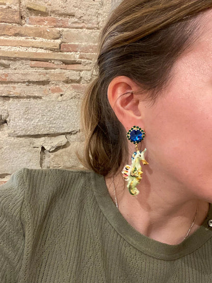 Person wearing colorful earrings with a stone wall background