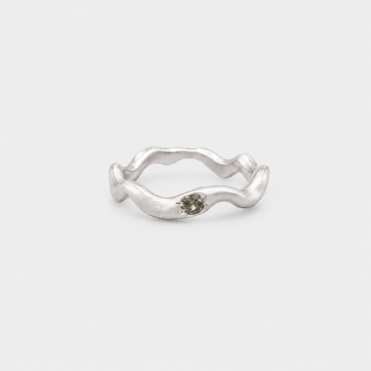 Silver ring with a small gemstone on a light gray background