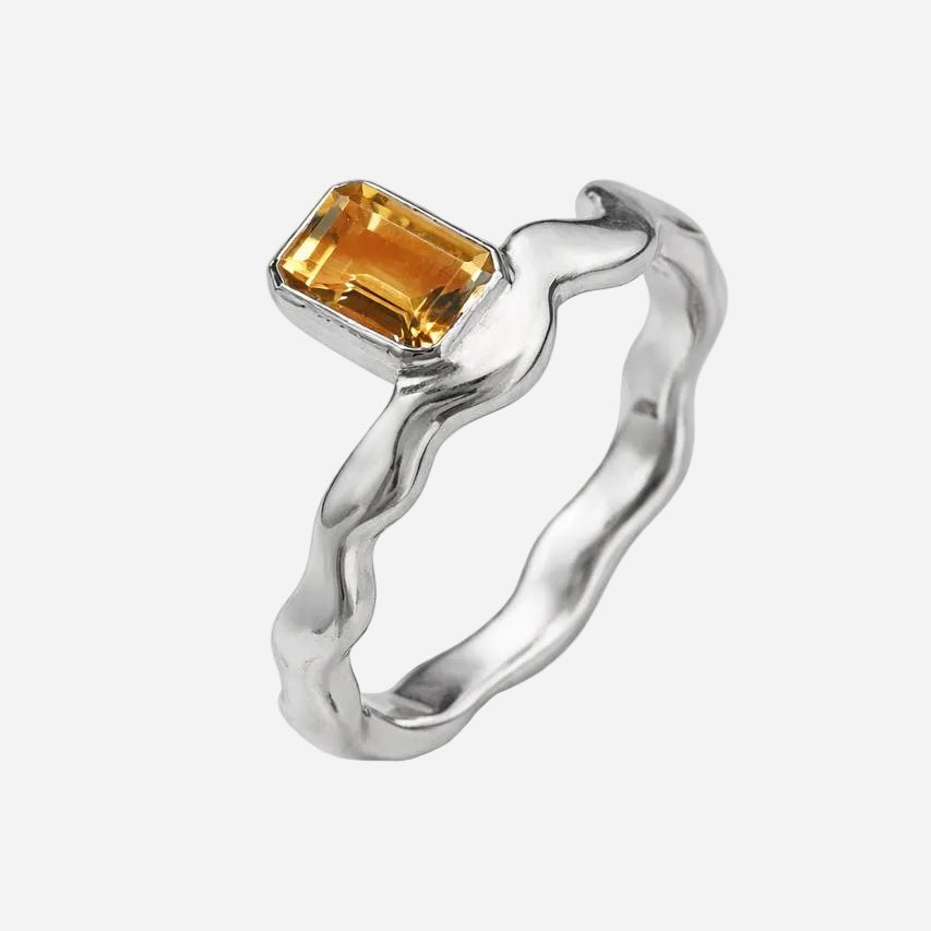 Silver ring with a yellow gemstone on a white background