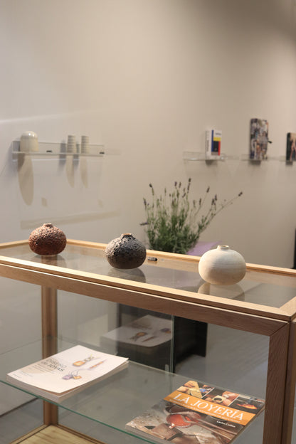 Glass display case with decorative items on a white wall