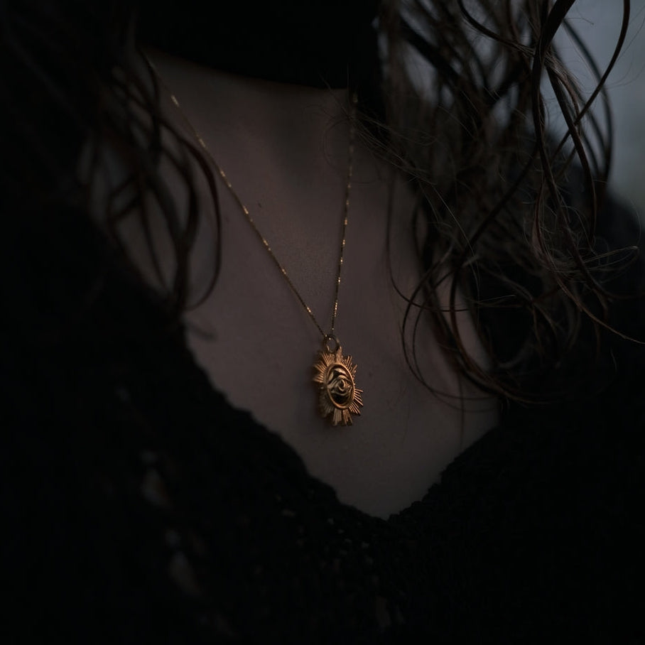 Necklace with a lion pendant worn by a person in a dark setting
